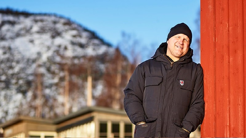Fredric Wedin ståendes vid Skulebergets fot, lutar sig mot det nya båthuset som byggts. 