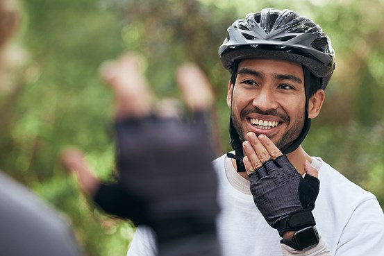 Man med cykelhjälm på använder teckenspråk för att kommunicera med en annan person.