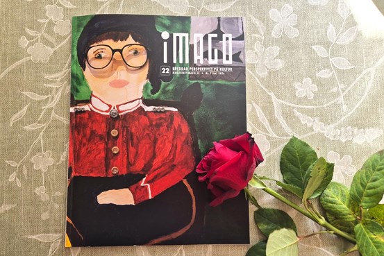 En tidning  med  en målad kvinnlig frälsningssoldat och titeln iMago på omslaget ligger på ett bord med en röd ros över.