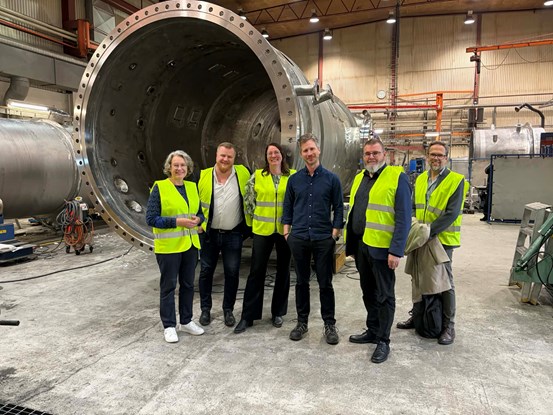 Delegation från Region Västernorrland står med representanter från Örnsköldsviks kommun i en industrilokal.