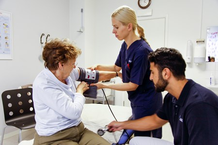 Patient får blodtrycket taget av vårdpersonal.