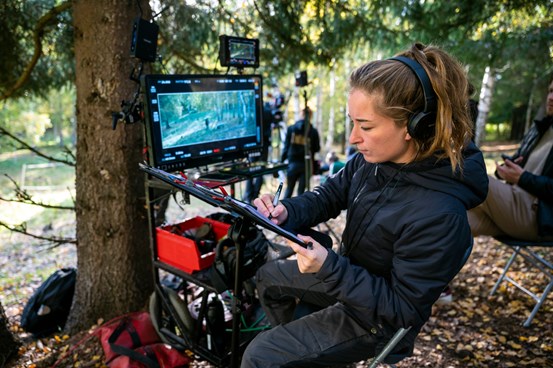 Filmarbetare sitter i skogsmiljö framför en digital skärm