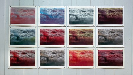 Tolv bilder i tre rader, fyra per rad, föreställande moln sedda uppifrån. De är i olika färgnyanser och har även mönster tryckta på. 
