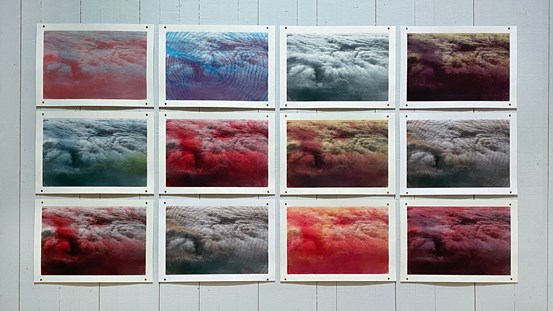 Tolv bilder i tre rader, fyra per rad, föreställande moln sedda uppifrån. De är i olika färgnyanser och har även mönster tryckta på. 