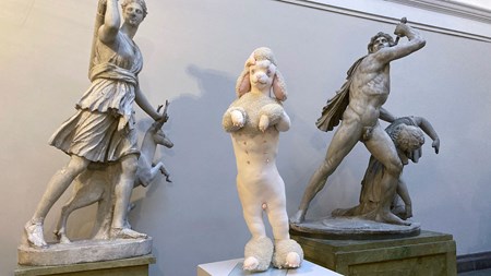Mellan två mer klassiska skulpturer står en textil skulptur. Den föreställer en vit, pudelliknande figur ståendes på sina bakben. 