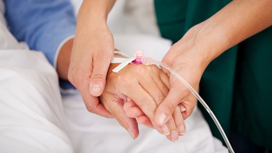 En sjuksköterska håller i en patients hand