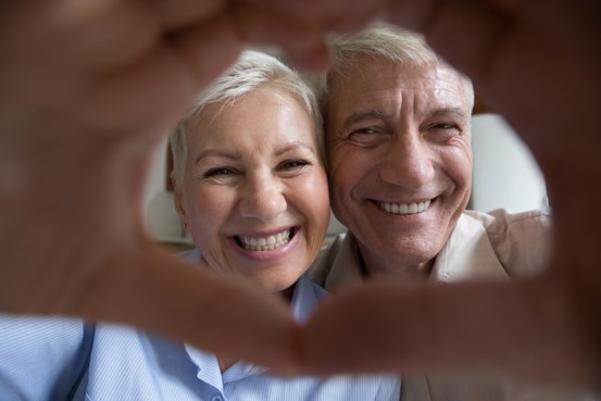 Äldre par som ser lyckliga ut i format hjärta av händer