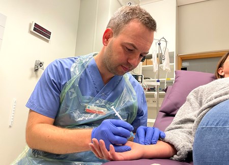 Läkare tar blodprov i handleden på patient