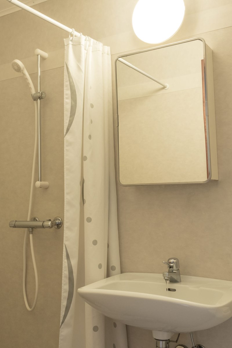 Ett badrum med handfat, spegel och dusch på internatet