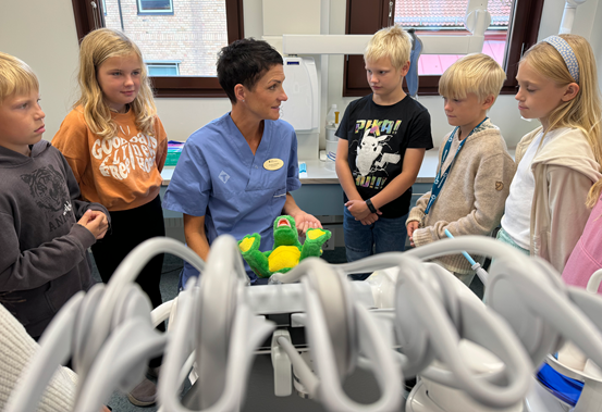 Barn står runt en tandhygienist i ett undersökningsrum.