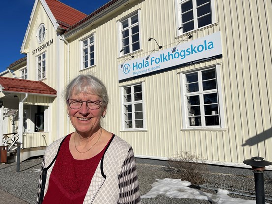 Glad kvinna framför Hola folkhögskolas byggnad.