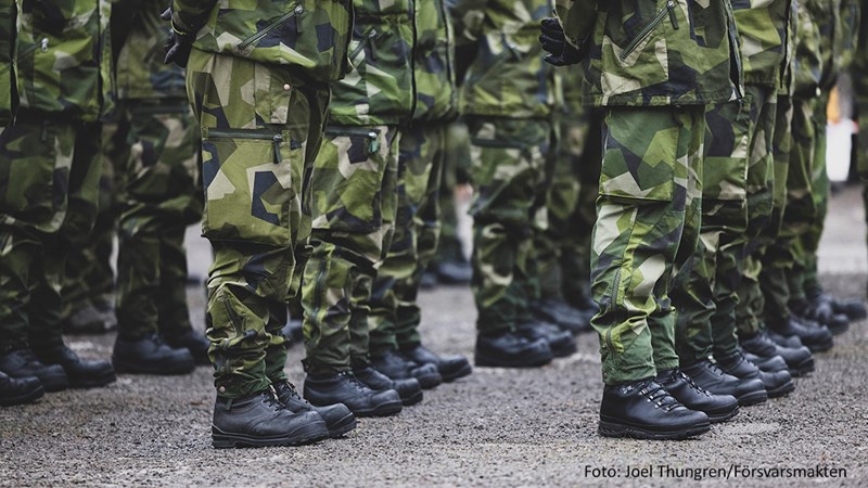 Bild på en grupp människor som är uppställda, där det syns en rad med skor och kamoflagefärgade byxor