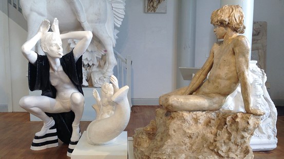 Cajsa von Zeipels skulptur av en delvis avklädd kvinna som gör kaninöron med händerna och räcker ut tungan åt Carl Milles skulpterade nakna yngling.