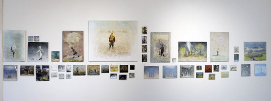 Foto. På en vit vägg hänger 49 bilder i emalj med varierande motiv. 