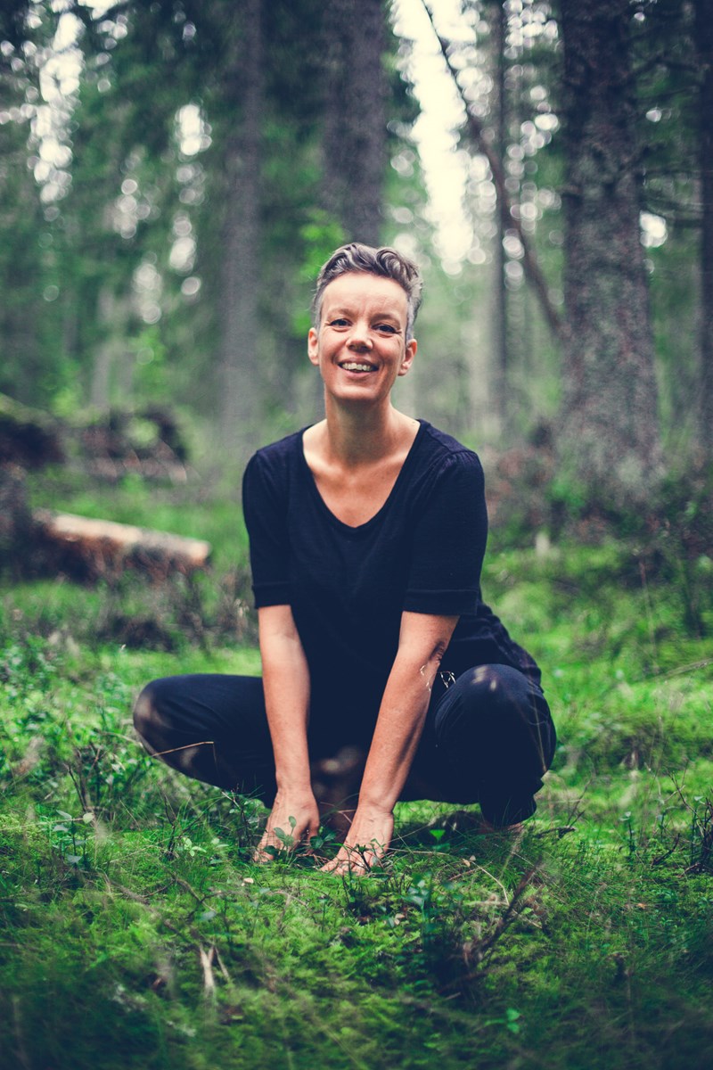 Kvinna sittandes på huk i skogen