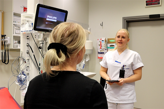 Josefina Bergqvist samtalar med en patient i ett rum på akutmottagning. Det är bara ryggen och bakhuvud av patienten som syns på bilden. 