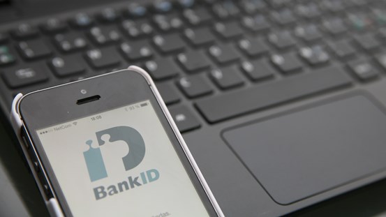 Mobil med bank-id ligger vid ett tangentbord redo att logga in via mobilen