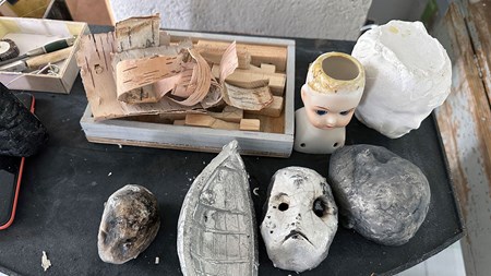 Arbetsyta i ateljén med björknäver, keramikmasker och andra saker.