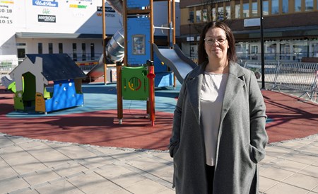 Emmi står utomhus på Kramfors torg. Bakom henne ser man barnens lekplats.