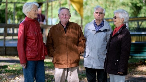 4 pensionärer står i grupp utomhus.