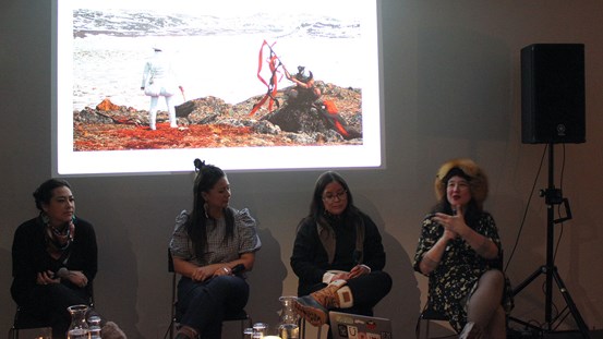 Fyra personer sitter på rad framför en projicerad bild av ett konstverk.