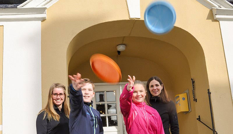 Två ungdomar kastar upp  frisbee i luften