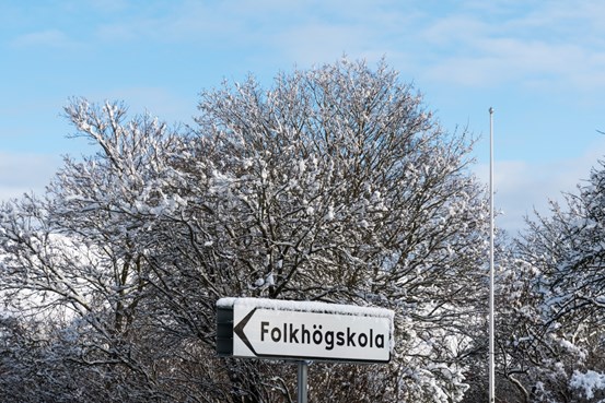 Skylt i vinterlandskap med texten folkhögskola 