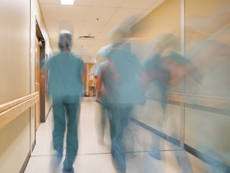 Anonym sjukvårdspersonal springer i en sjukhuskorridor