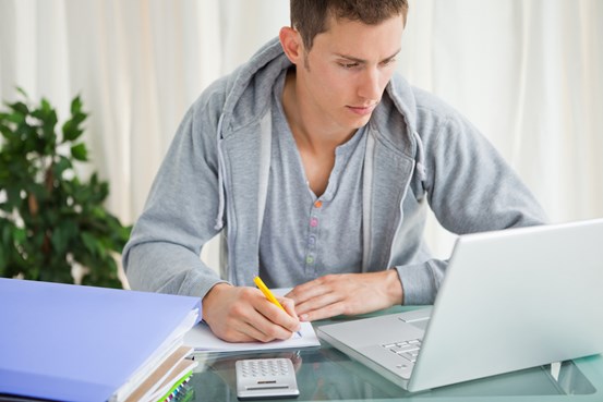 Studentkille som läser böcker och skriver anteckningar. 