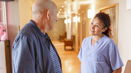 En sjuksköterska samtalar med en patient i en korridor