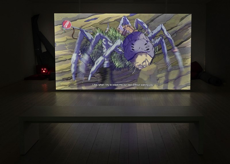 Dokumentation av videoinstallation med animerad lila spindel som rör sig över en tippad STOP-skylt. Undertexten i stillbilden är: ”Like, when I try to crawl into our bed without waking you.”