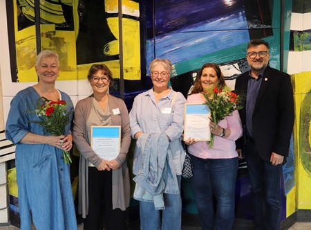Mottagarna av hållbarhetsstipendierna står framför ett konstverk i Regionens hus i Härnösand, med diplom och blommor. 