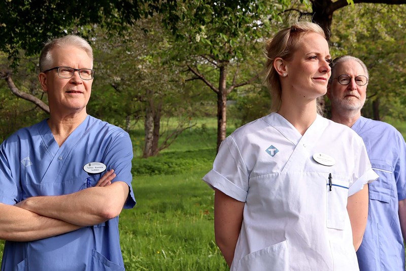 Handledare på tandakademin två män och en kvinna står utomhus framför träd.