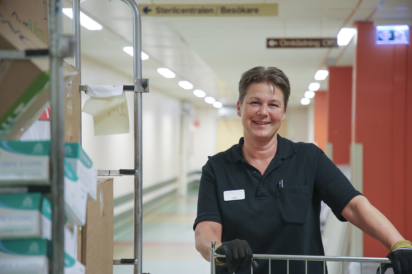 Lotta Nordlund ler, håller i en grind till en vagn med varor som levererats till sjukhuset.