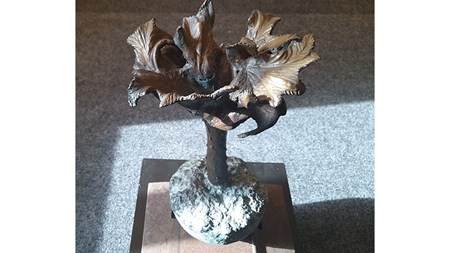 En skulptur i brons av en växt med kal stam och spretig krona. 
