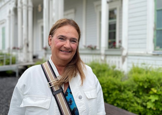 Lena Ljungberg, pensionerad tandsköterska står utomhus framför en byggnad.