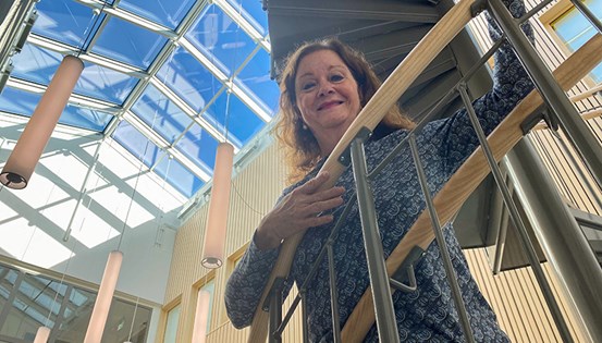 Anne-Lie Fahlén lutar mot ett trappräcke inomhus