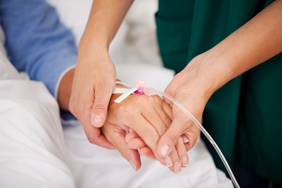 Sköterska håller en patients hand