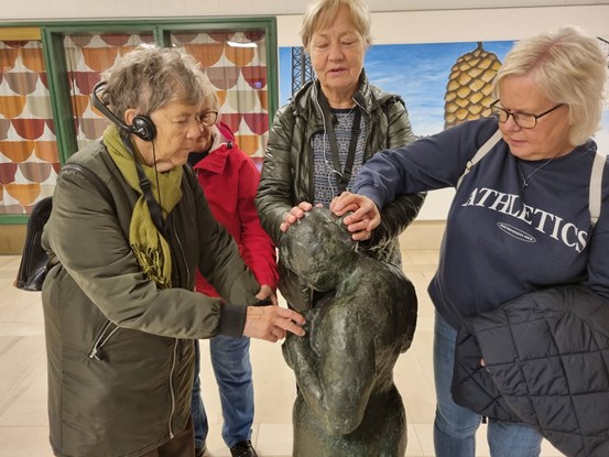 Deltagare på den syntolkade konstvisningen undersöker skulpturen Venus från Rätansbyn.  