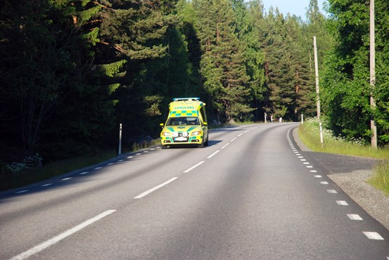 Ambulans åker på väg genom skog