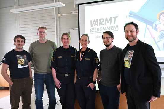 Gruppen står uppradad längst fram i lokalen bredvid varandra. 