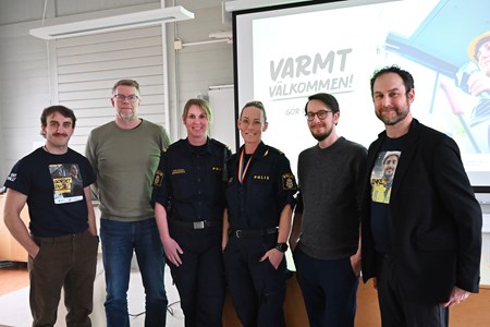 Gruppen står uppradad längst fram i lokalen bredvid varandra. 