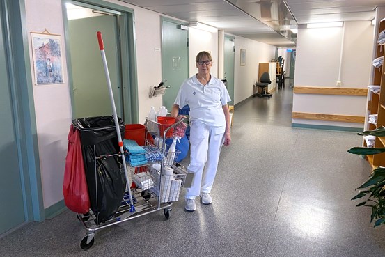 Ingela Andersson står med en städvagn i en korridor på hälsocentralen i Ånge