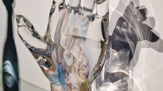 Foto. En hand i transparent glas med en ingjuten bild.