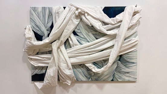 En rektangulär, liggande målning föreställande ett knutet, lindat, vitt lakan mot en mörk bakgrund. Runt målningen är ett vitt lakan knutet och virat. 