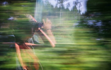 Resenär på ett tåg, sitter vid fönstret med naturlandskap utanför.