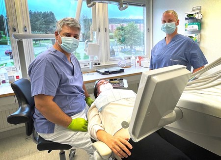 Patient får tandvård av tandläkare och tandhygienist i ett undersökningsrum.
