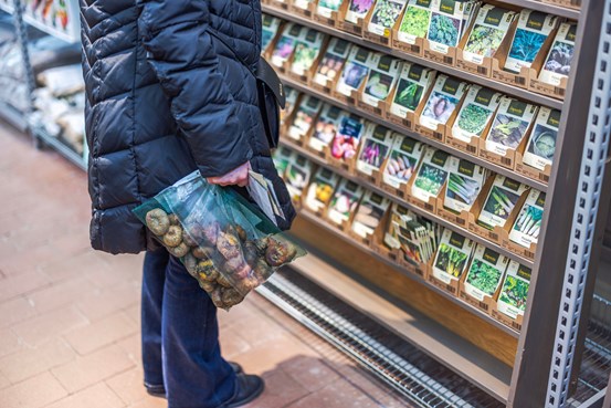 En kund som håller i en påse potatis i en livsmedelsbutik