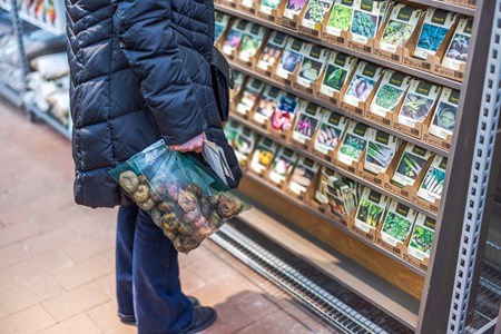 En kund som håller i en påse potatis i en livsmedelsbutik