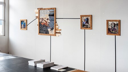Fyra inramade kollage hänger i ett utställningsrum, tre mindre och en större. Samtliga tavlor är sammanlänkade av svart eltejp som även leder ner till högar av tidskrifter travade på golvet.